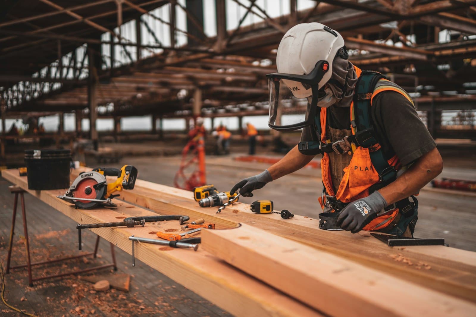 A worker measuring timber on a fabrication floor